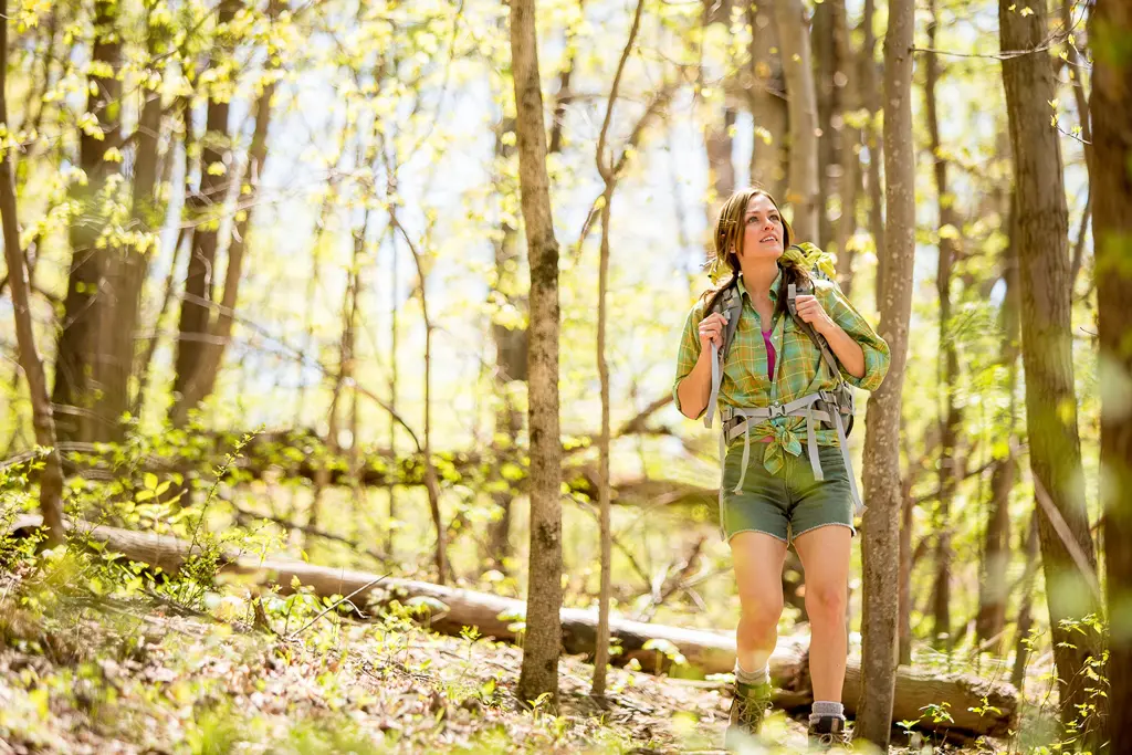 Young white woman happily hikes in the woods on a sunny spring day in Botetourt County, VA.