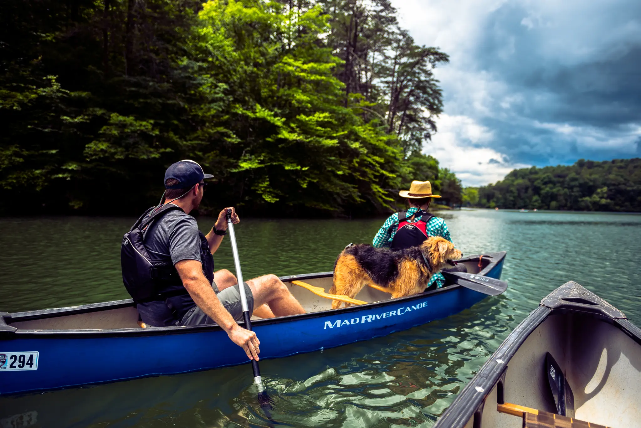 Two white men and a dog paddle a canoe in Philpott Lake in Franklin County, VA