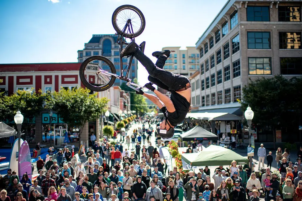 BMX cyclist is flipping through the air in front of a crowd of onlookers in downtown Roanoke at the annual Roanoke GO Outside Festival