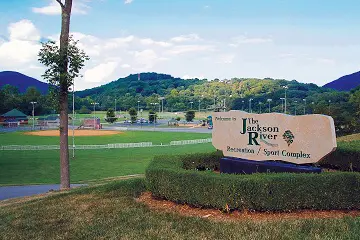 Exterior shot of the Jackson River Sports Complex. It's a sunny day with tree covered mountain background.