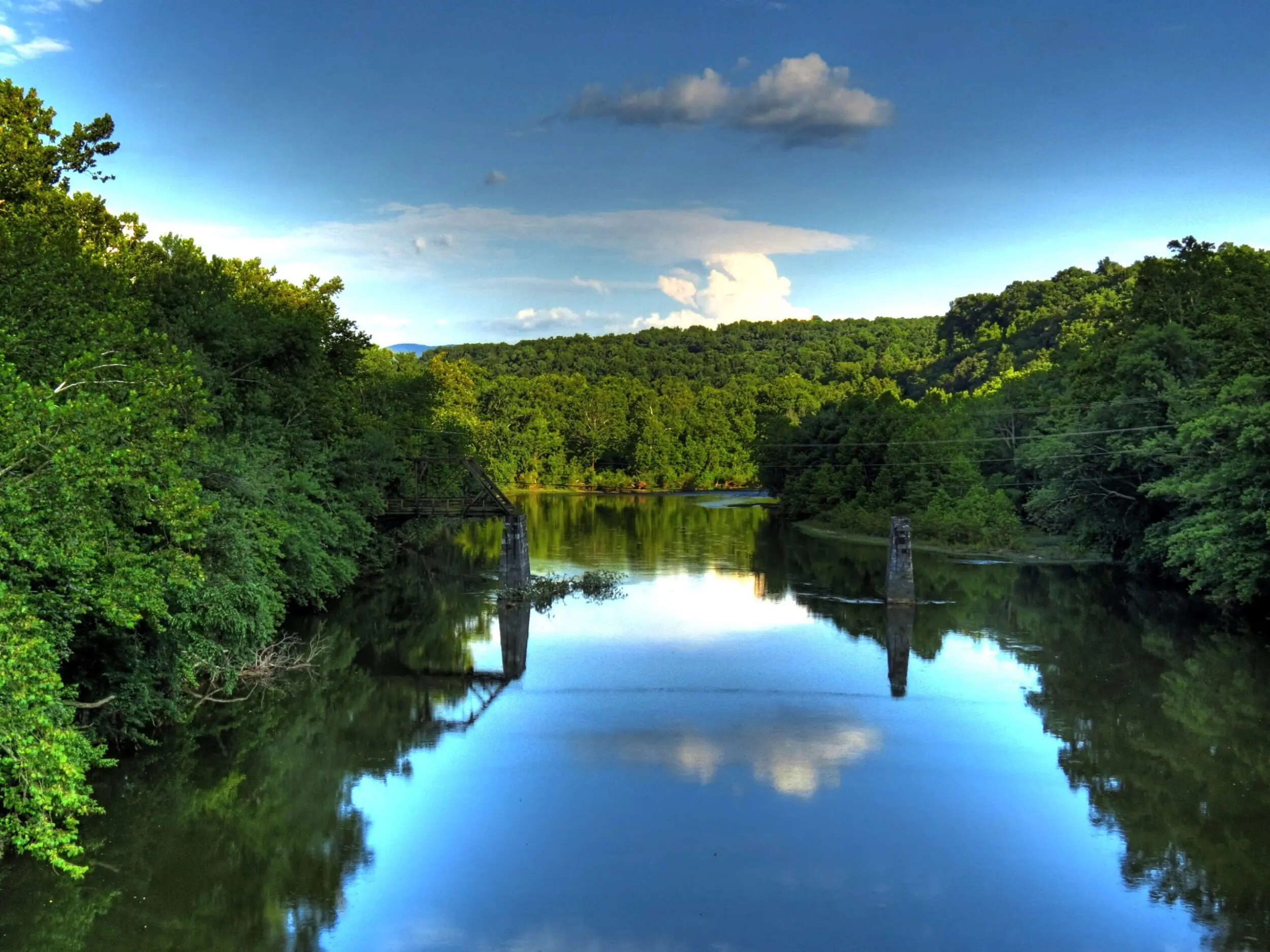 Beautiful shot of the James River in Botetourt County. The river is lined with lush green trees and the blue sky is reflected in the still river.