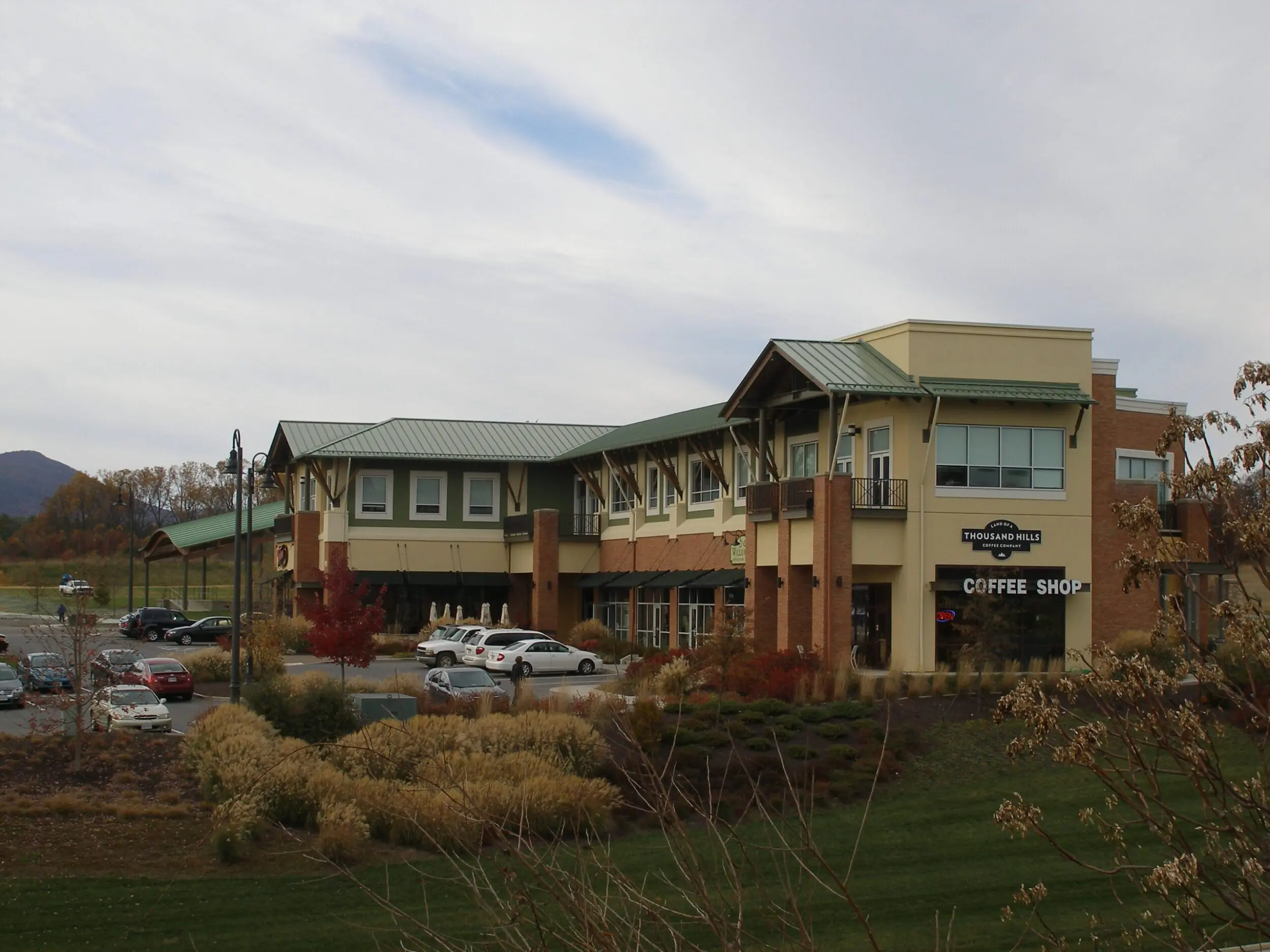 Exterior shot of Thousand Hills Coffee Shop in the Daleville Town Center in Botetourt County, VA. It is a cloudy day in late autumn as most trees don't have leaves and bushes in the landscaping are brown.