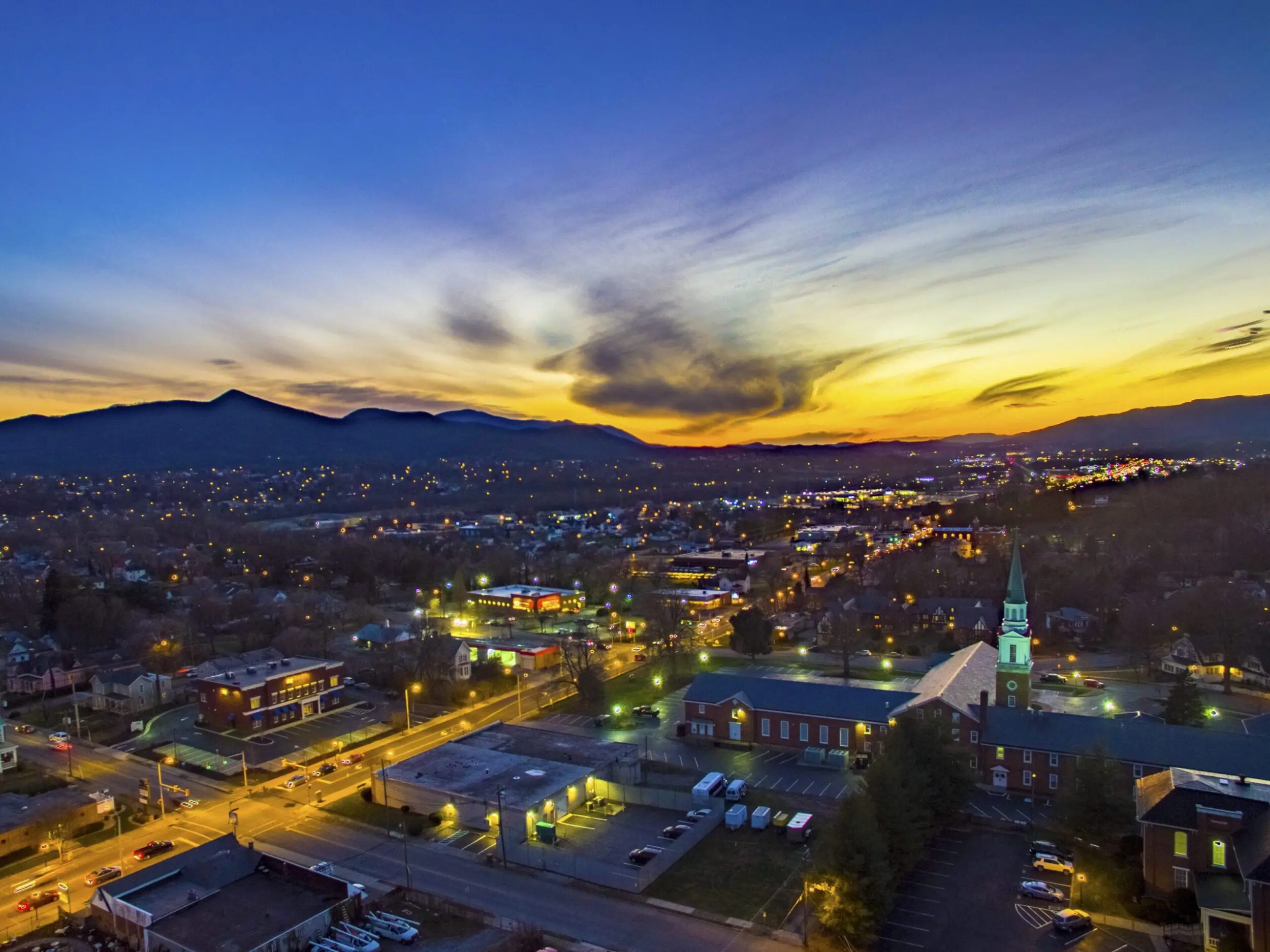 Winter sunset drone shot of downtown Salem with shops and churches lit up.