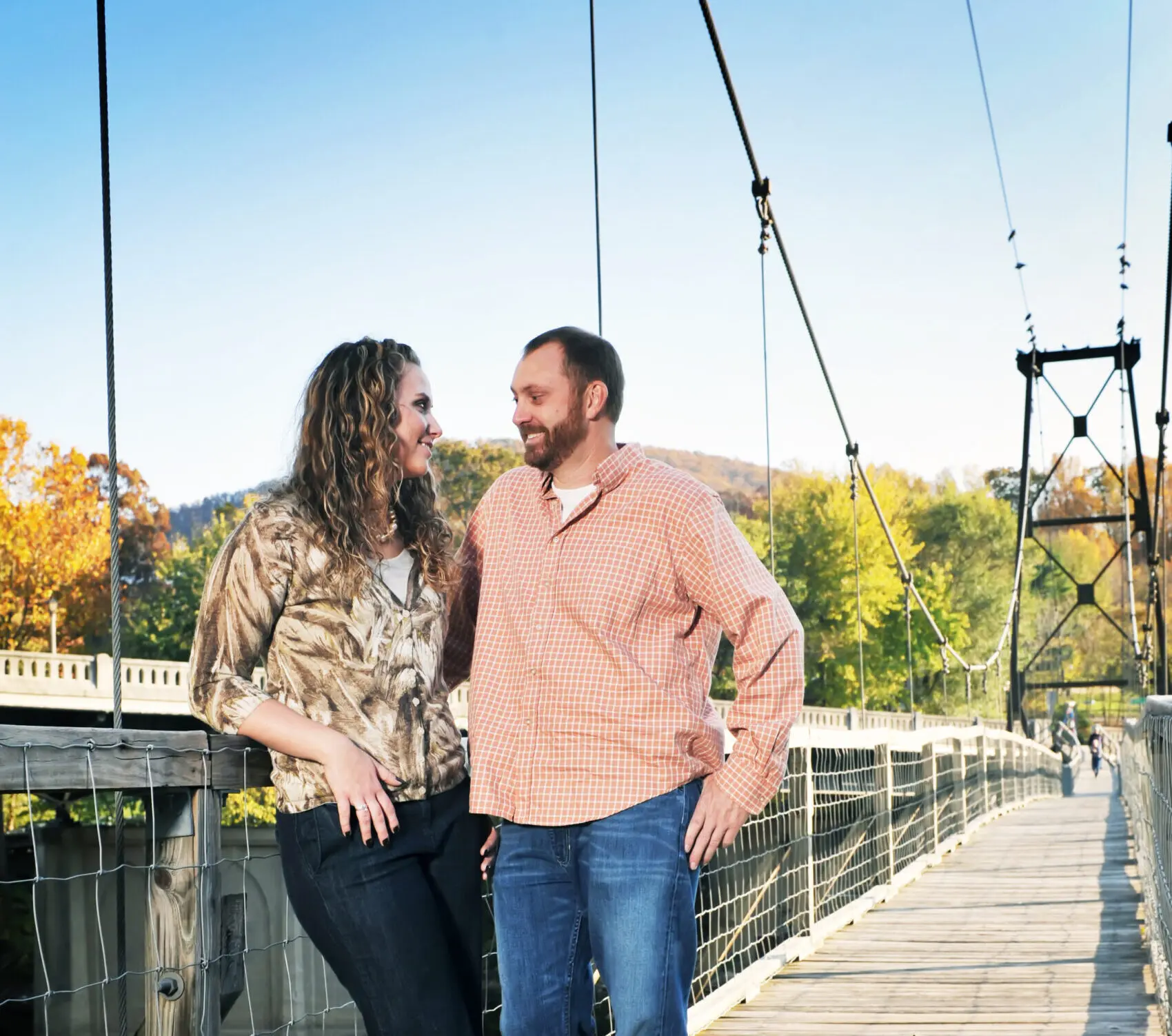 A white couple in their 30s stares lovingly at one another as they stand on the Swinging Bridge in Buchanan, VA.