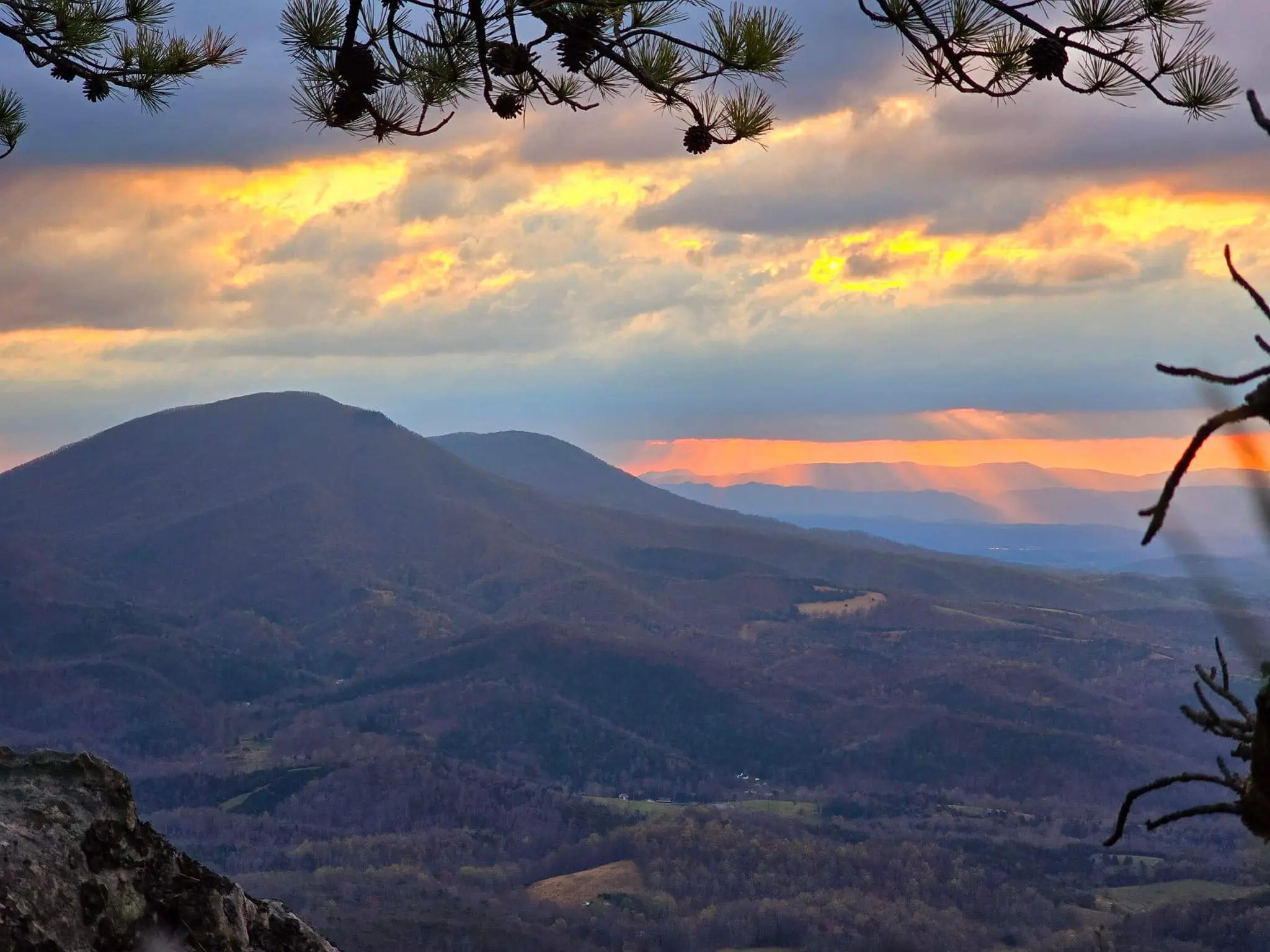 Bowers North Mountain in Alleghany County at sunrise as the sun peaks through the clouds.