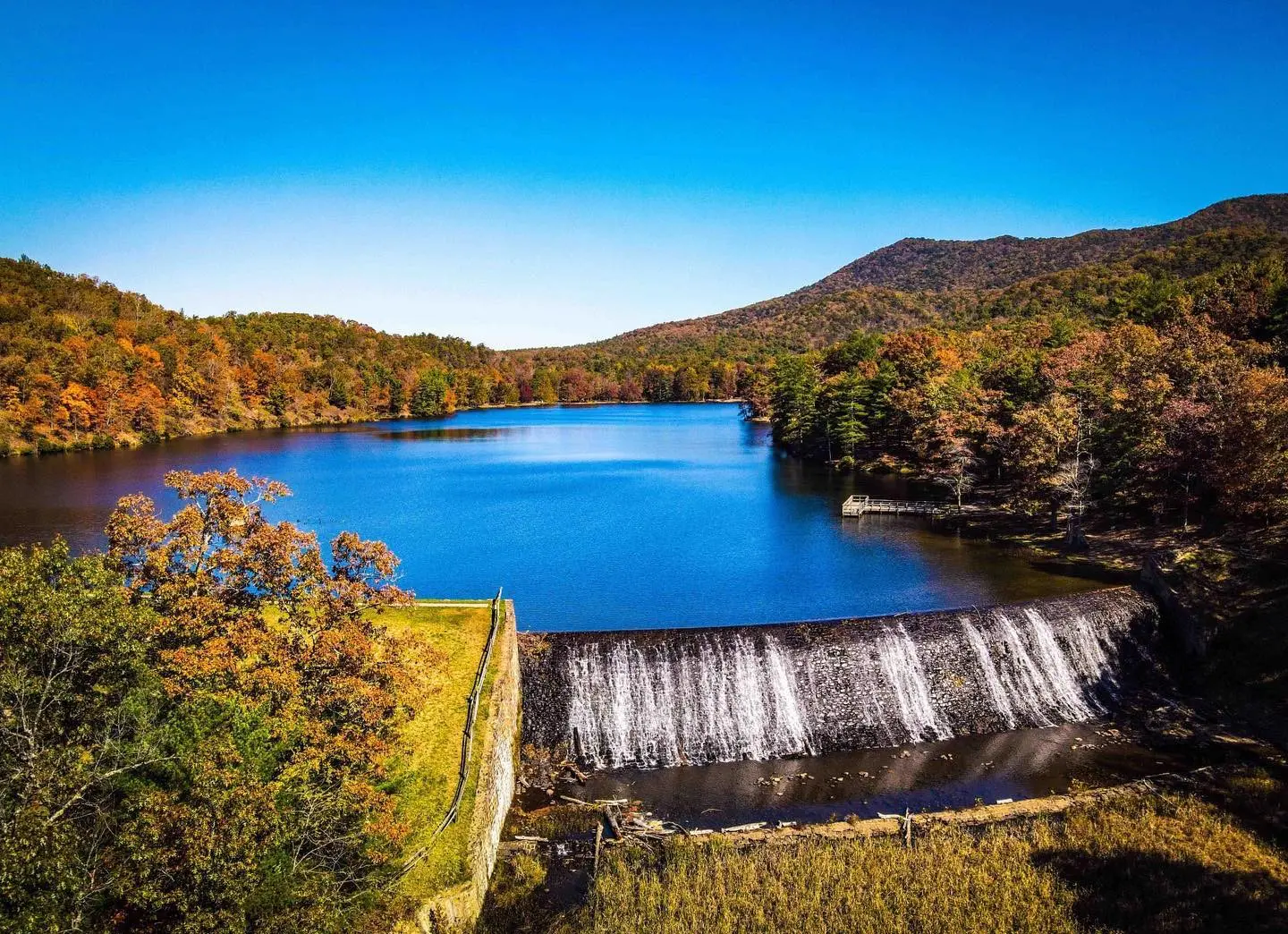 Aerial shot of Douthat Lake in early autumn on a sunny, cloudless day.