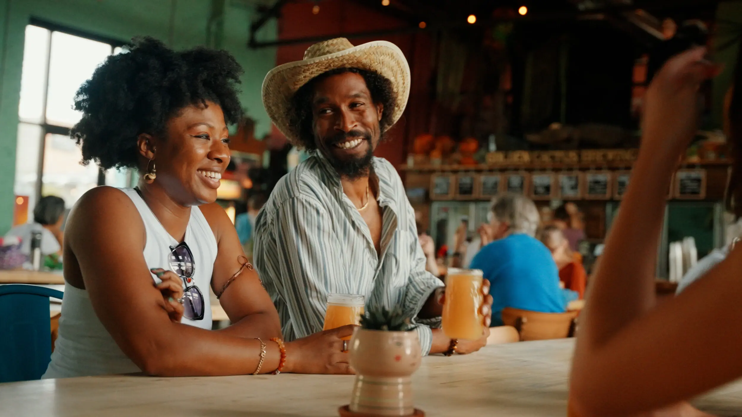 A young Black woman and young Black man sit in a brewery in Roanoke, Virginia.