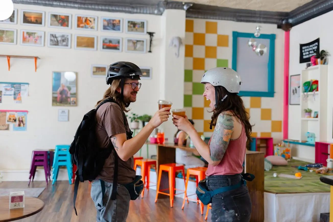Two bikers, one male one female, cheers-ing in Second Cafe