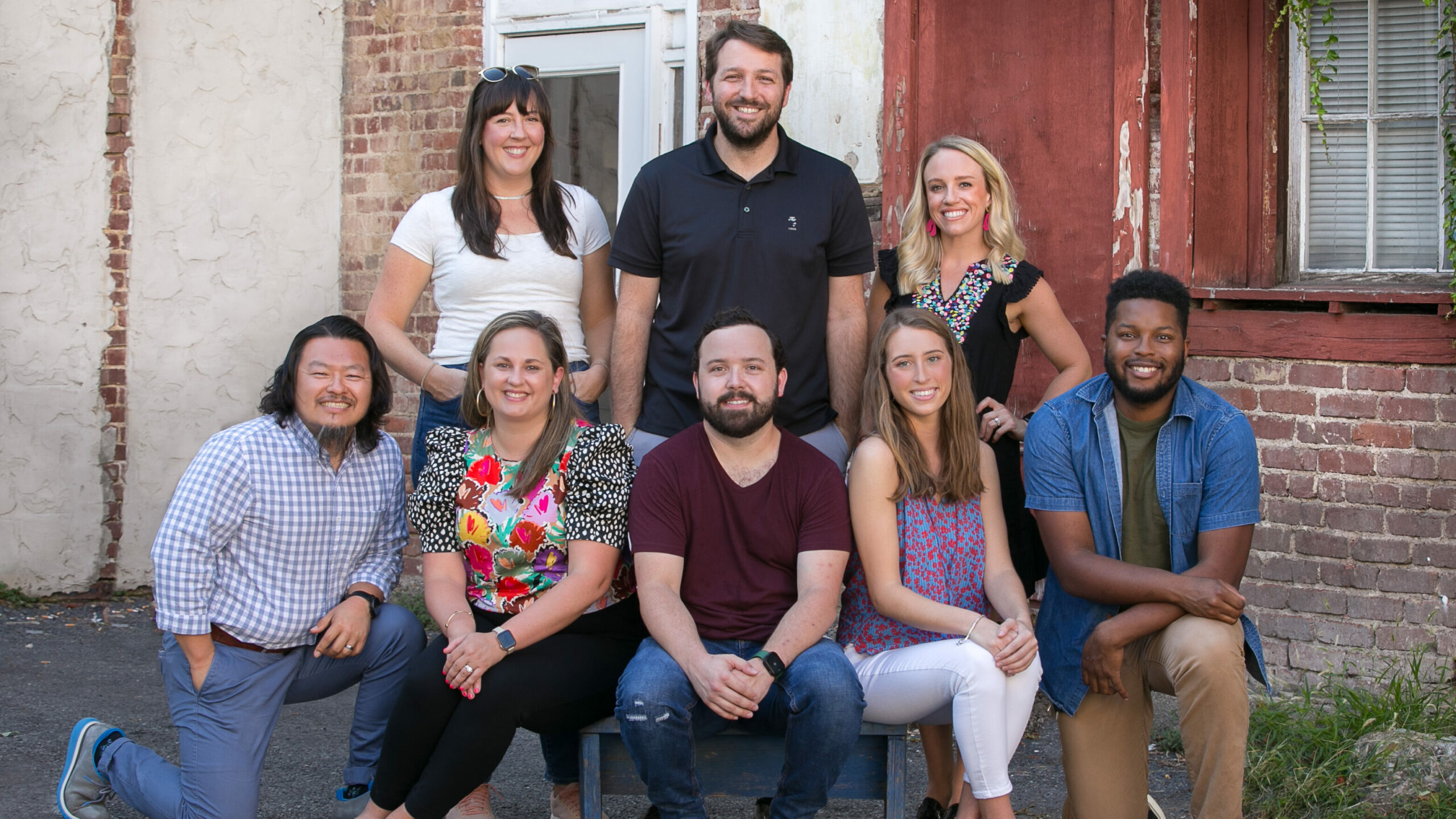 Diverse group of young to mid-career professionals in an urban setting,posed and smiling for the camera.