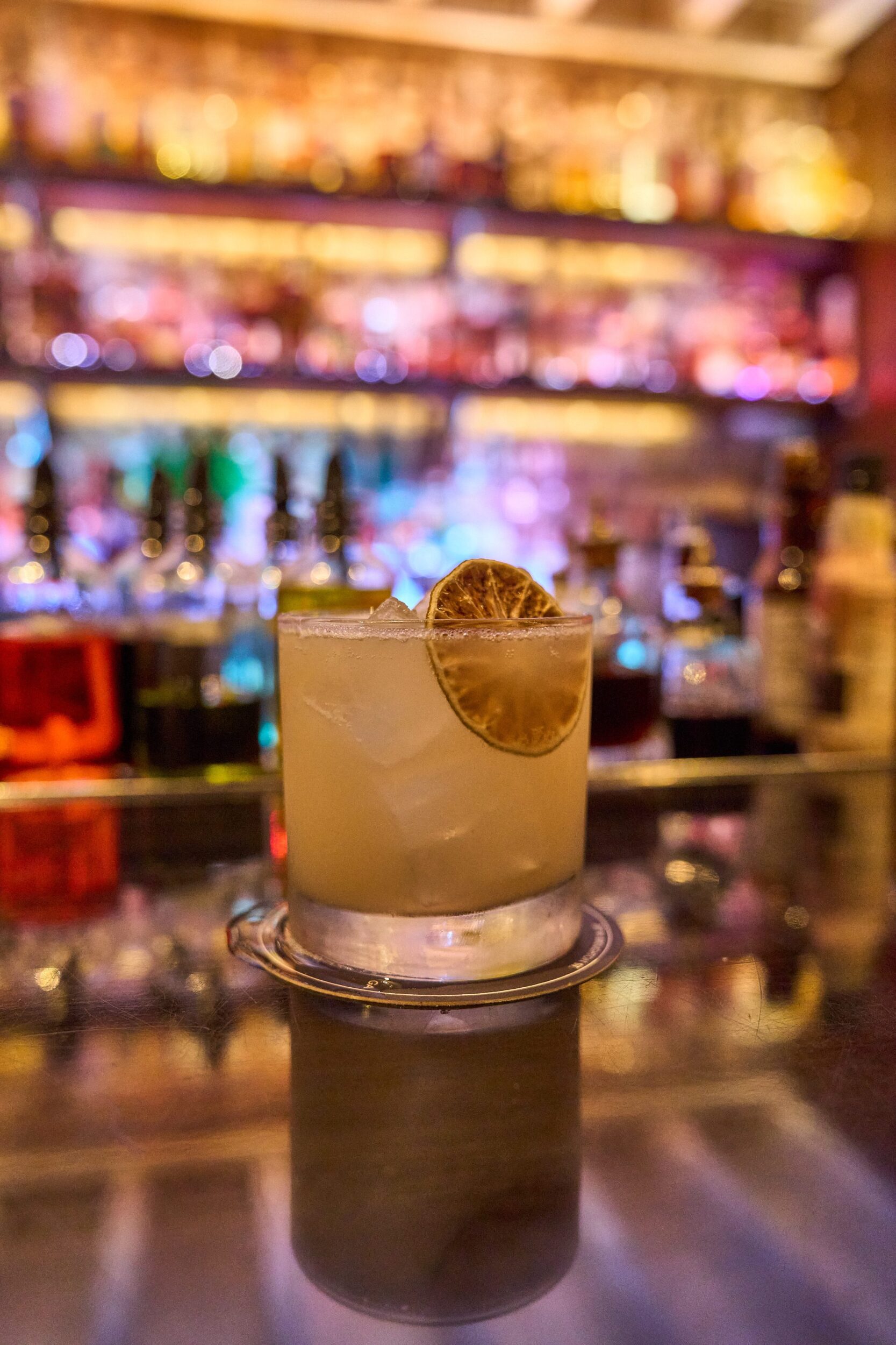 Cocktail on a bar with colorful lighting in the background.