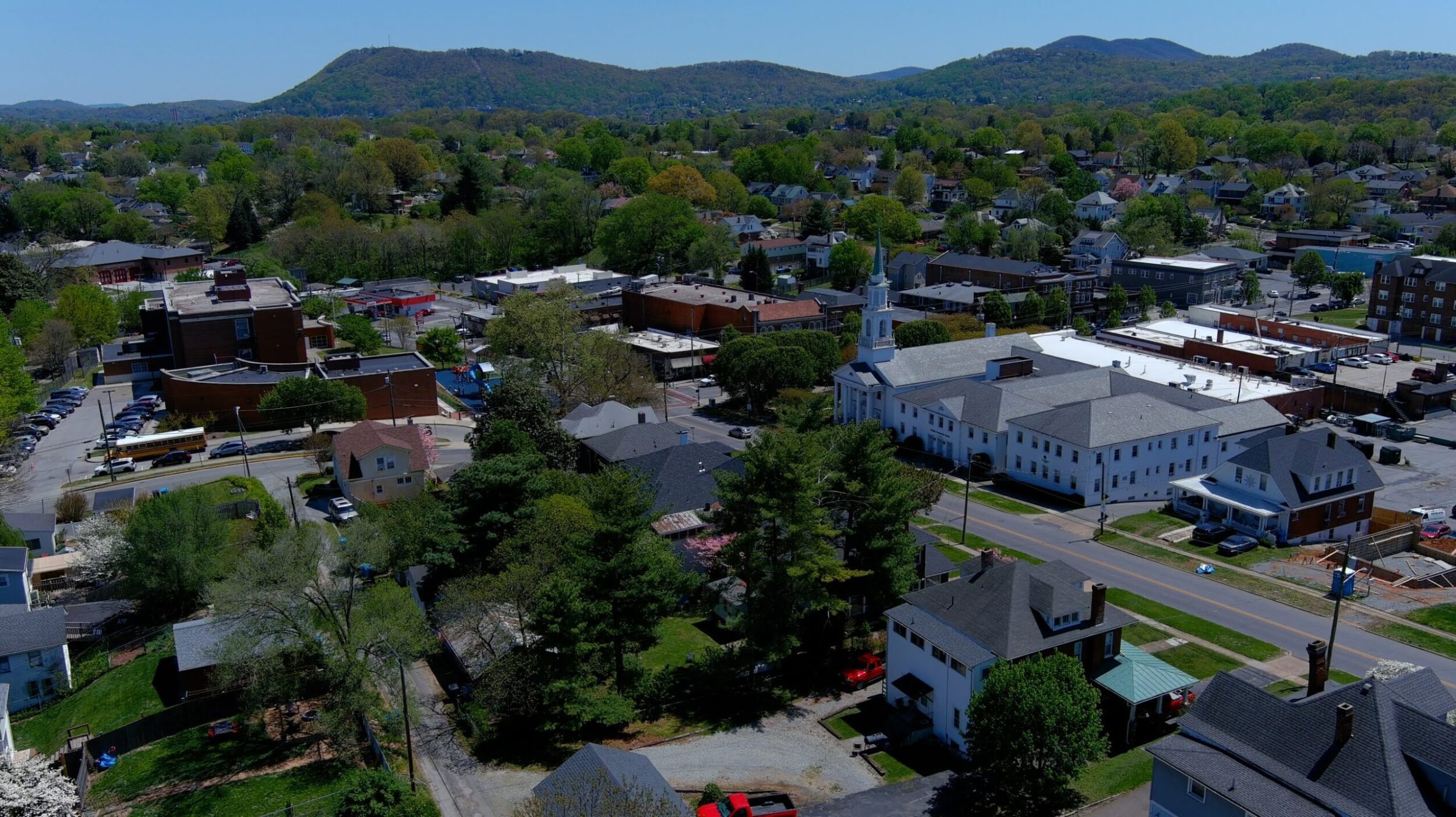 Overhead shot of the Grandin Village neighborhood in Roanoke, VA. It's a sunny, summer day with green trees and mountains in the background.