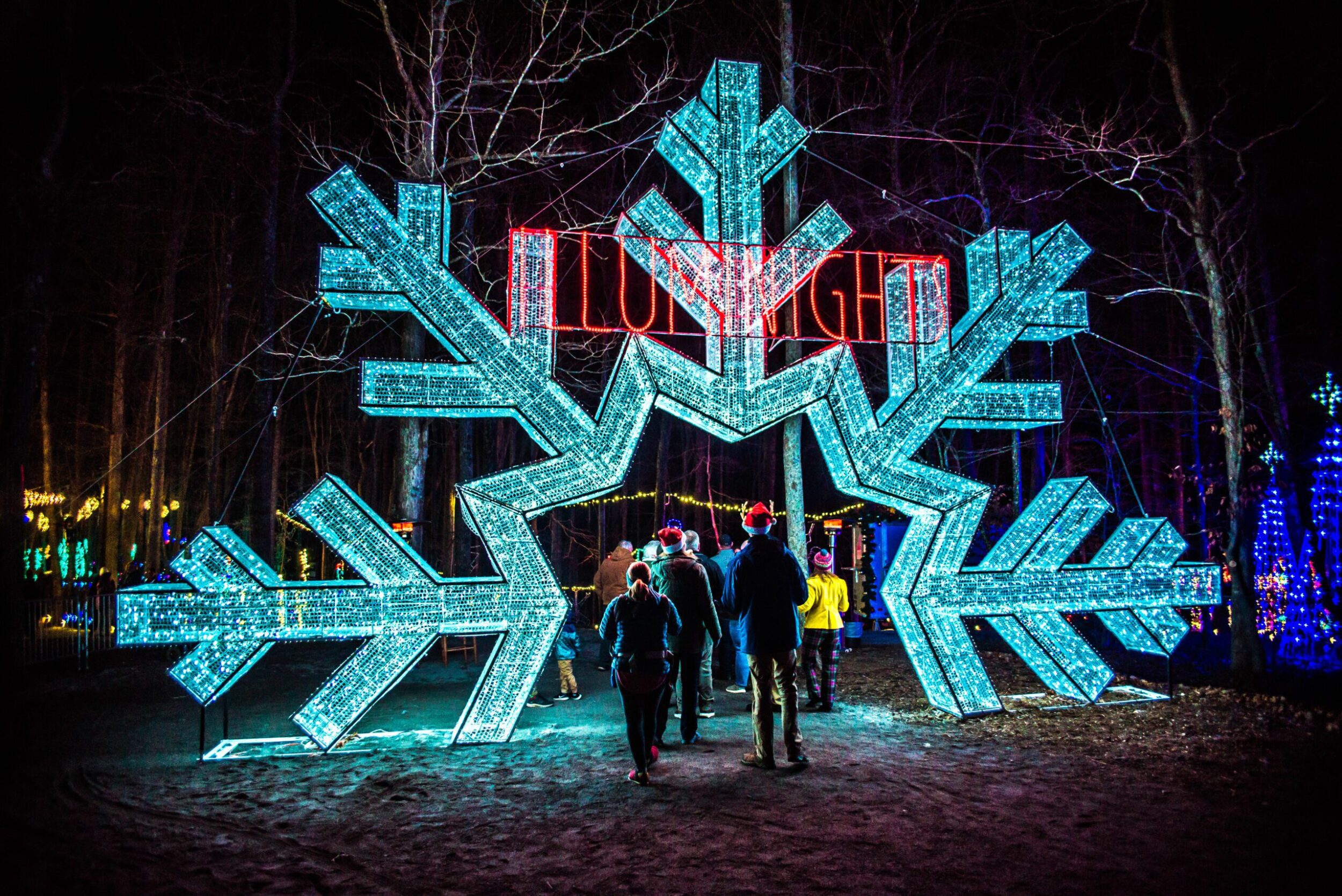 A giant illuminated snowflake with an "Illuminights" sign above it stands as the entrance to the Illuminights holiday attraction in Explore Park in Roanoke County, VA.