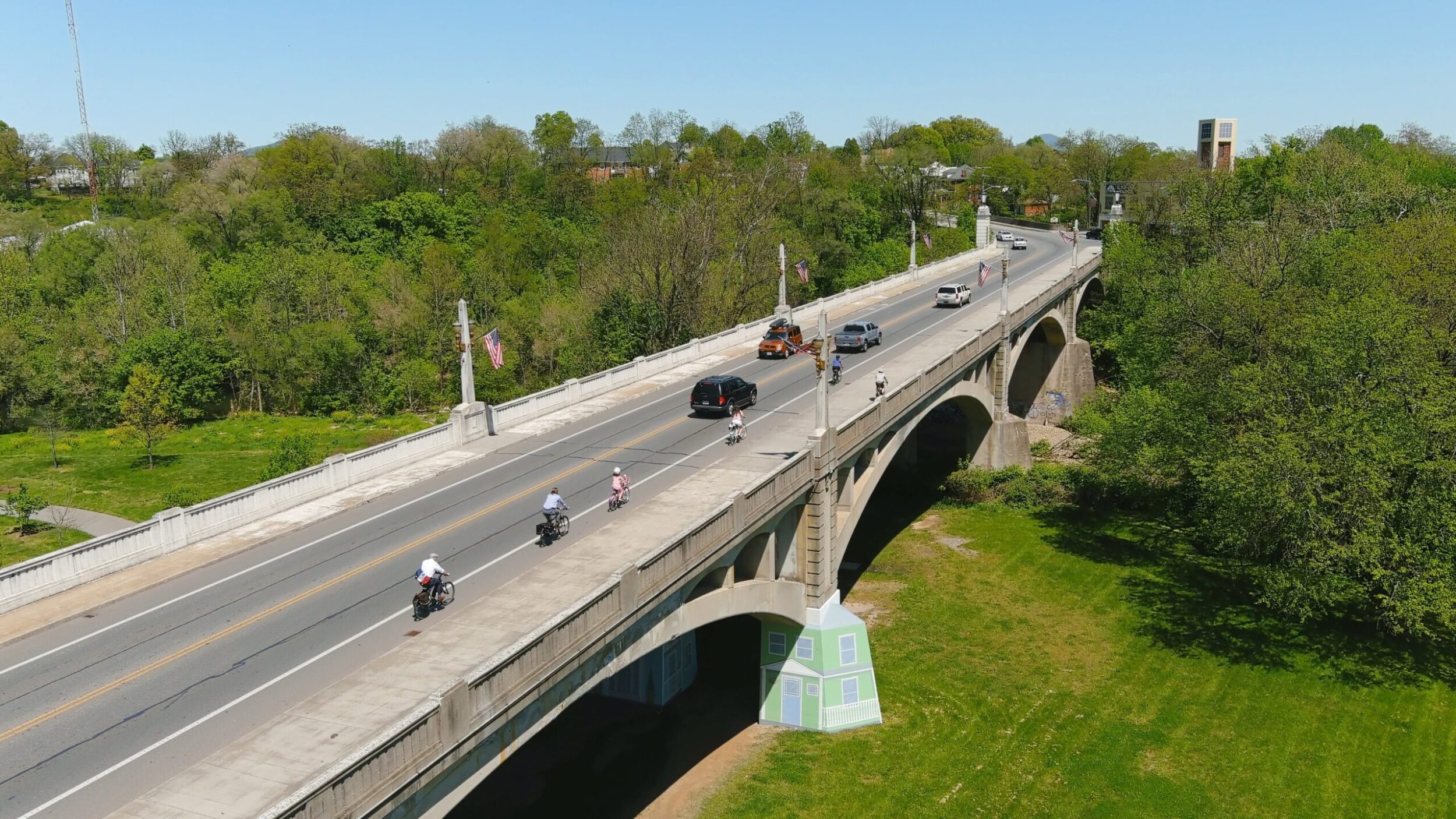 Memorial Bridge in Roanoke, VA with cyclists and cars driving across on a sunny summer day.