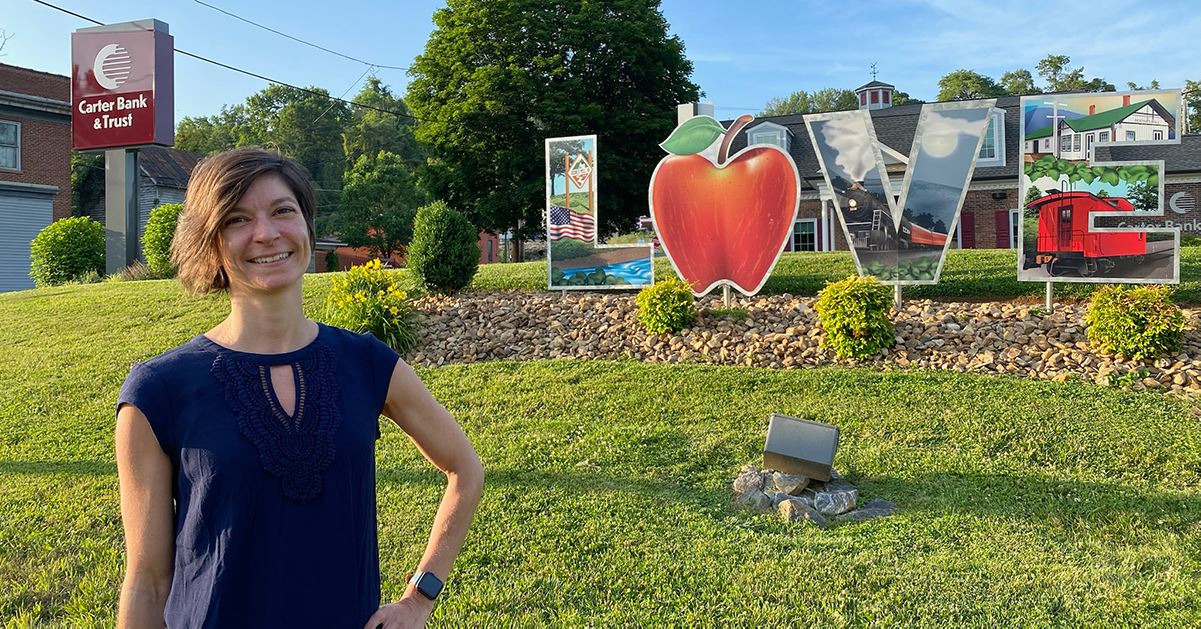 Local farmer, Olivia, poses in front of a Virginia Tourism Corporation "Love" sign on a beautiful, sunny day.