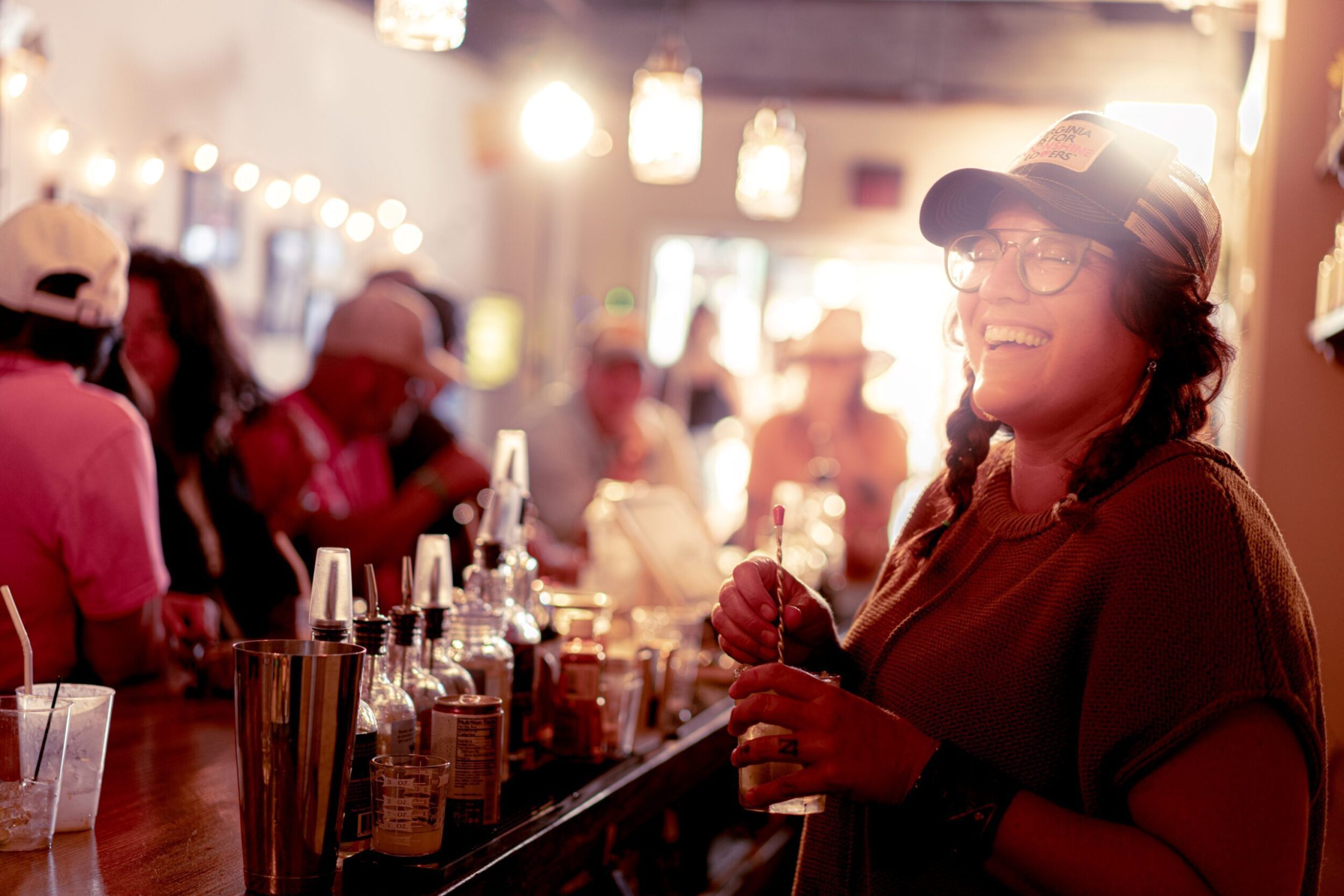 A server at Twin Creeks Distillery laughs behind the bar as she mixes a drink.