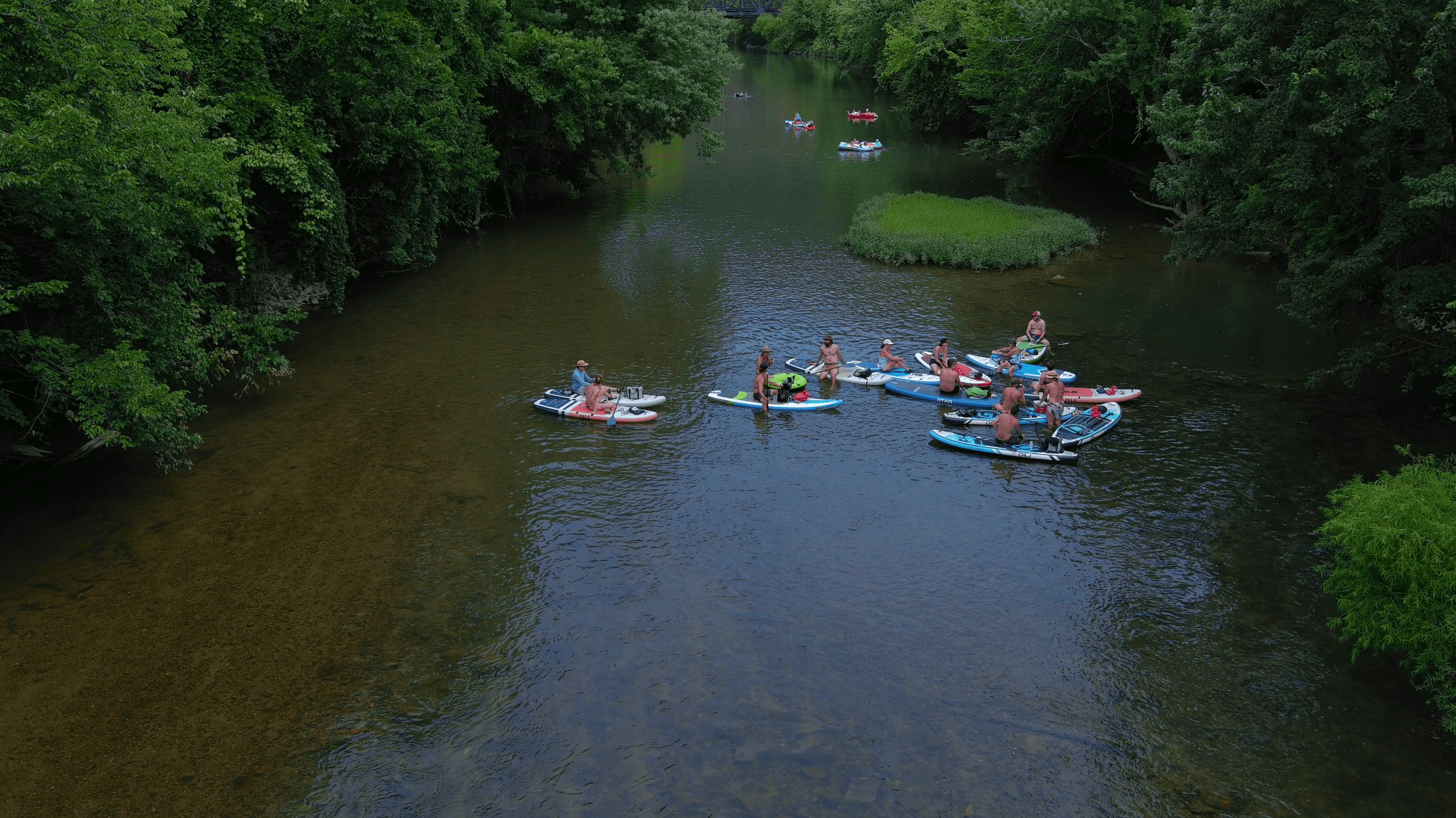 A group of paddleboarders float on the Roanoke River on a sunny summer day.