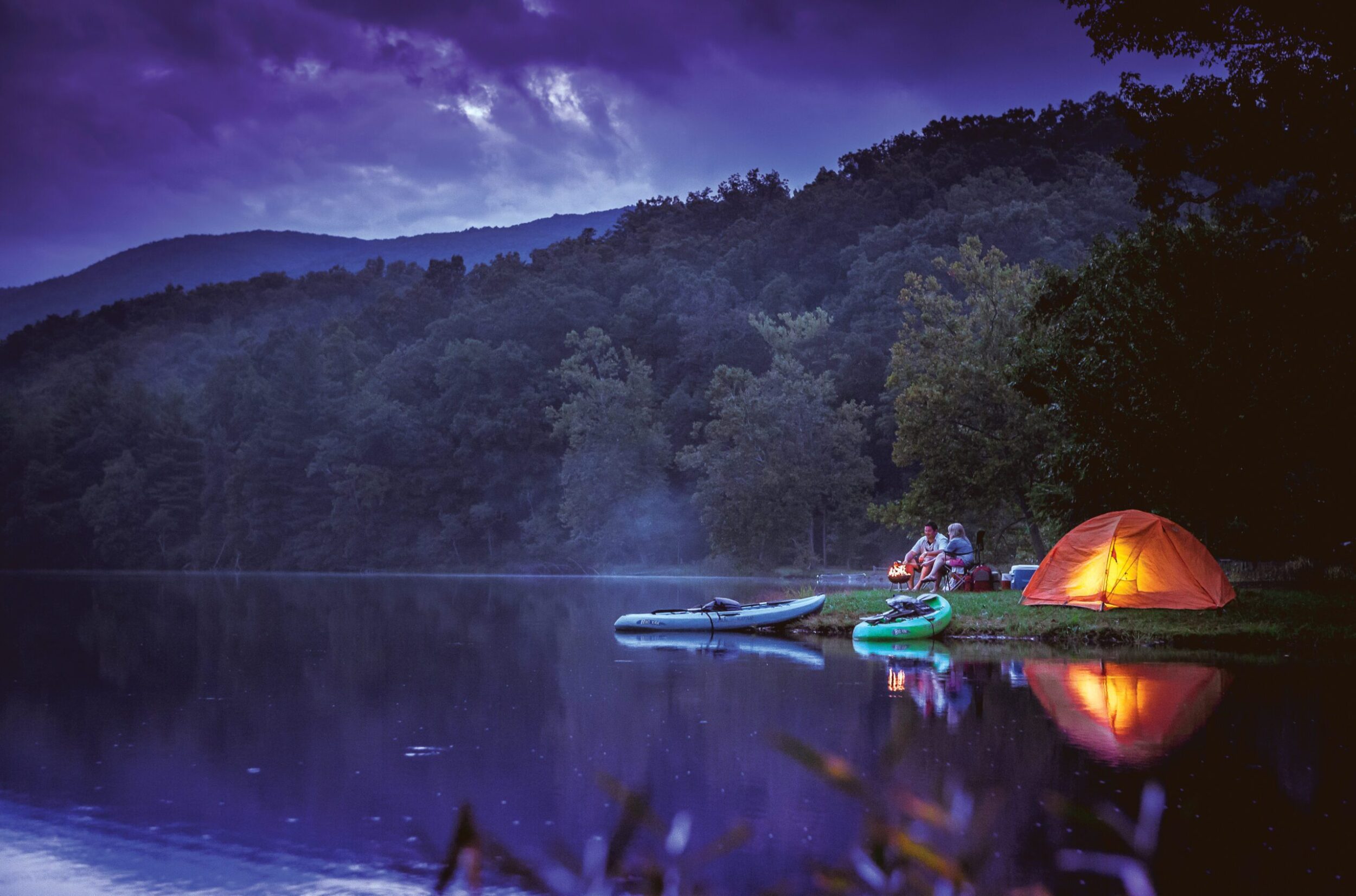 Kayaks and paddleboards pulled ashore at a campsite at Douthat State Park at dusk.