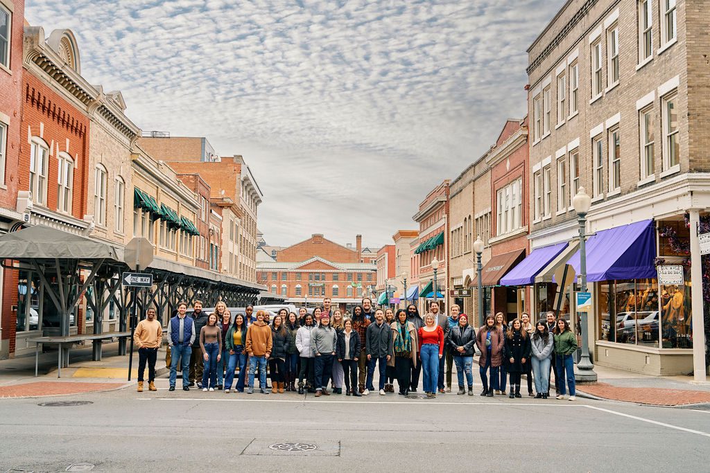 The 2025 Roanoke Region Talent Ambassador Cohort. A diverse group of around 50 young to mid-career professionals are gathered on a street in downtown Roanoke. They're all looking at the camera smiling.